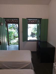 a bedroom with a bed and a desk and two windows at Pousada do Ipe in Goiás