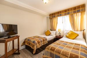 um quarto de hotel com duas camas e uma televisão de ecrã plano em Park Plaza Apartments em Santiago