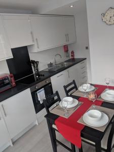 a kitchen with white cabinets and a table and chairs at LT Grove Apartment - Stratford in London