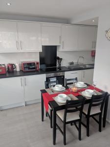 una cucina con tavolo e sedie neri e una cucina con armadietti bianchi di LT Grove Apartment - Stratford a Londra