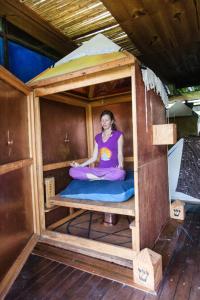 a woman sitting inside of a wooden house at Yolitia Wellness in Malinalco