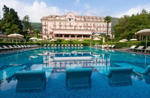 a hotel swimming pool with chairs and a building at Hotel Simplon in Baveno