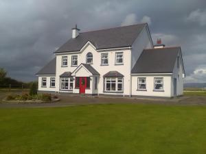 a large white house with a red door at Lisduvogue House in Ballina