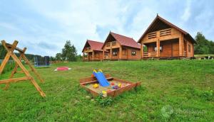uma casa de madeira com um parque infantil em frente em Domki Letniskowe w Sercu Natury em Świerkocin