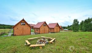 Domki Letniskowe w Sercu Natury في Świerkocin: تكدس الخشب في حقل بجانب بعض المنازل