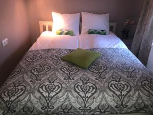 uma cama grande com lençóis brancos e almofadas verdes em Villa Kadriorg Hostel em Taline