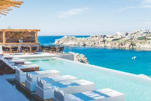 einen Pool mit Stühlen, Tischen und Meerblick in der Unterkunft Super Paradise Hotel in Super Paradise Beach
