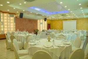 a banquet hall with white tables and chairs and a screen at Chris & Eve Mansion in Komotini