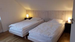 two beds in a hotel room with two lamps at Gites Chez Schangala in Thannenkirch