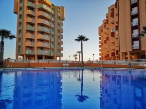 a swimming pool in front of two tall buildings at Los Miradores in La Manga del Mar Menor