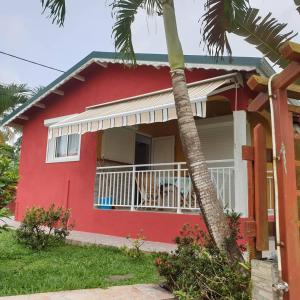 a red house with a dog sitting on a balcony at Atlantic Gites in Capesterre-Belle-Eau