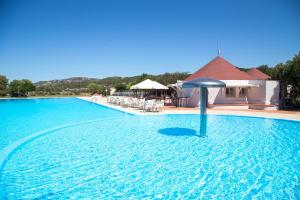 a swimming pool with an umbrella in the water at Cugnana Porto Rotondo Bungalows - Camping in Cugnana