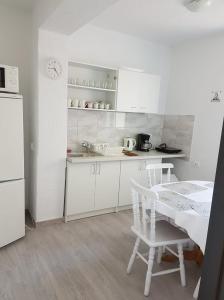 a white kitchen with a table and a white refrigerator at Marynarska 19 in Darłówko