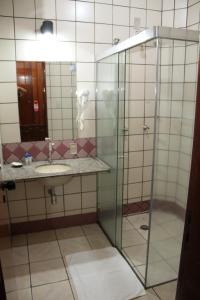 a bathroom with a glass shower and a sink at Hotel Taiyo in Caldas Novas