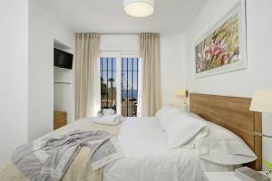 a white bedroom with a bed and a window at Casa de la playa Alto de el Realengo in La Herradura