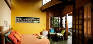a bedroom with a bed and a yellow wall at Pousada Casa Milà in Ubatuba