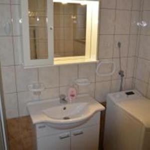 biała łazienka z umywalką i lustrem w obiekcie Apartments Denis & Lucija w Rovinj