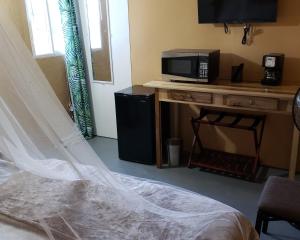 a bedroom with a bed and a microwave on a desk at Viva Violas in Port Antonio