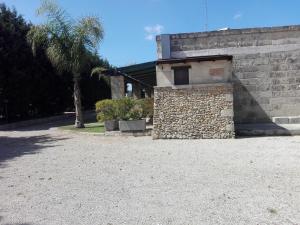 un edificio con una pared de piedra y una palmera en Appartamenti turistici Aprile Luca, en Borgagne