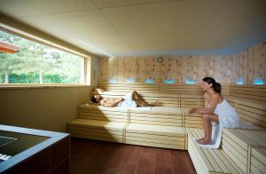 Eine Frau, die mit zwei Personen in einer Sauna sitzt. in der Unterkunft Vitalhotel der Parktherme in Bad Radkersburg
