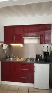 a kitchen with red cabinets and a sink at Parvis de la cathédrale de Bayeux vue directe in Bayeux