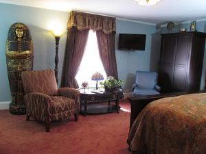 ein Schlafzimmer mit einem Bett, einem Stuhl und einem Tisch in der Unterkunft VacationHouse in Ulster Park