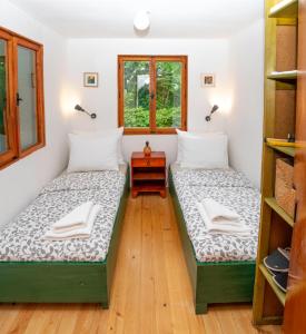two beds in a room with a table and windows at Mika’s Garden in Bled