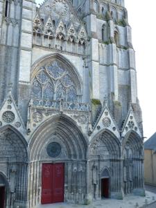 a large cathedral with red doors and a tower at Parvis de la cathédrale de Bayeux vue directe in Bayeux +1 photo