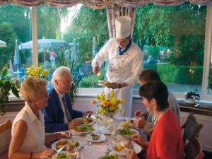 grupa ludzi siedzących przy stole z szefem kuchni w obiekcie Haus am Meer Steinhude w mieście Wunstorf