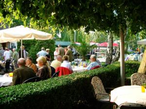 a crowd of people sitting at tables in a garden at Haus am Meer Steinhude in Wunstorf