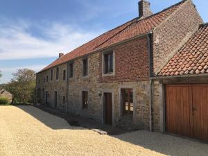 un ancien bâtiment en briques avec un garage dans l'établissement Le charme de l’Estroit, à Mettet