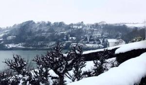 a snow covered mountain with a town and a body of water at Bay View B&B Glandore in Glandore