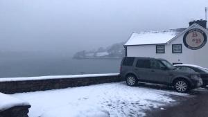 ein Auto, das vor einem Gebäude im Schnee parkt in der Unterkunft Bay View B&B Glandore in Glandore