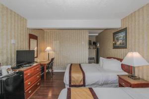 a hotel room with two beds and a tv at Canadas Best Value Inn Chinook Station in Calgary