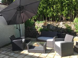 eine Terrasse mit einem Sonnenschirm, Stühlen und einem Tisch in der Unterkunft East Bank Apartment in Grange Over Sands