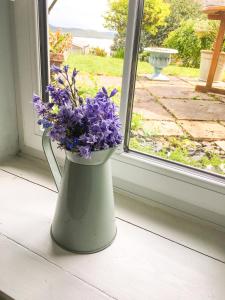 a vase filled with purple flowers sitting on a window sill at Garden Apartment in Grange Over Sands