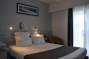 Un dormitorio con una cama con almohadas blancas y una ventana en Hotel De Bretagne, en Saint-Pierre-Quiberon