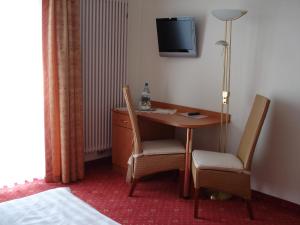 a hotel room with a desk and chairs and a television at Panorama Hotel am Frankenstein in Witzelroda