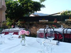 albergo ristorante coppa في Dazio: طاولة مع كؤوس للنبيذ وورد في مزهرية