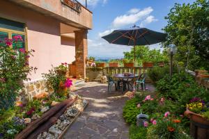 eine Terrasse mit einem Tisch, einem Sonnenschirm und Blumen in der Unterkunft Poggio della Roverella Country House in Morlupo