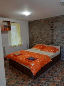 a bedroom with a large bed with an orange comforter at Andrei in Sasca Montană