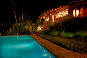 a swimming pool in front of a house at night at Pousada Casa Milà in Ubatuba