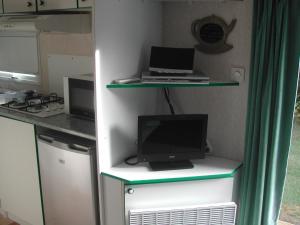 een kleine keuken met een bureau en een computer bij mobil home dordogne in Mouzens
