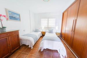Zimmer mit 3 Betten und einem Holzschrank in der Unterkunft Luminoso adosado frente al mar in El Médano