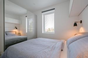 a white bedroom with two beds and a window at Apartment Fresh - Parking included in Izola