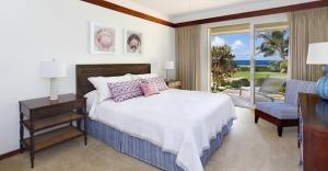 a bedroom with a bed with a view of the ocean at Whalers Cove in Poipu in Koloa