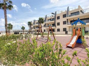 une aire de jeux avec deux équipements de jeux devant un bâtiment dans l'établissement Apartment Playa Elisa Bay, à Pilar de la Horadada