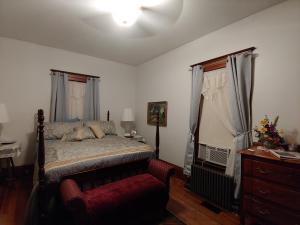 1 dormitorio con 1 cama y 1 silla roja en Delano Bed and Breakfast, en Wichita