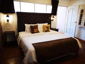 1 dormitorio con 1 cama grande con sábanas y almohadas blancas en Cities of the World - Apartments Cusco, en Cusco
