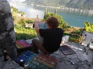 a person sitting on a rock looking out at a river at Apartments Jovanović in Perast